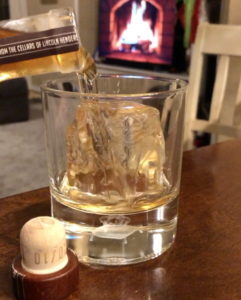 Pouring whiskey over crystal clear ice cube
